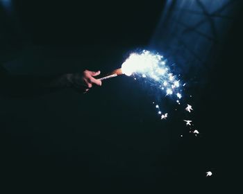 Cropped hand holding firework at night