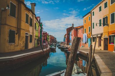 Canal amidst houses against sky in city