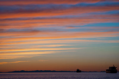 Scenic view of sea against dramatic sky during sunset