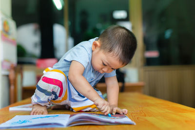 Boy drawing on book at table