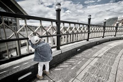 Rear view of man standing on bridge against sky