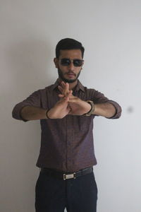 Portrait of young man standing against gray background