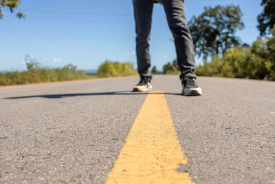 Low section of man skateboarding on road