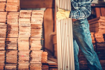 Low section of man standing on stack of firewood