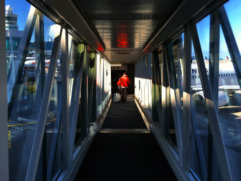 Man walking on passenger boarding bridge at airport runway