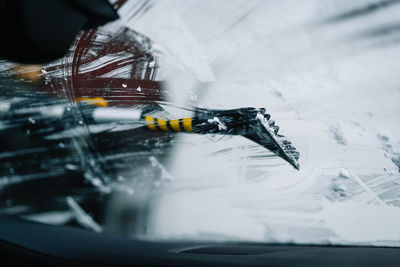 High angle view of snow tool cleaning car windshield in winter