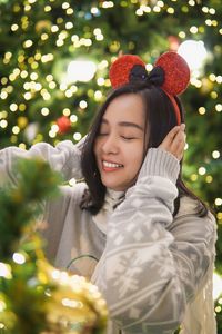 Portrait of young woman standing against christmas tree