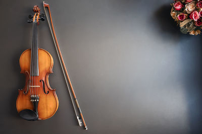 High angle view of violin and flowers against gray background