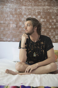 Young man sitting on his bed