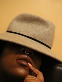 Woman wearing hat against yellow wall