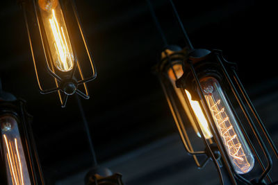 Low angle view of illuminated light bulbs hanging indoors