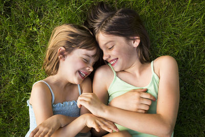 Two sisters lying in meadow having fun