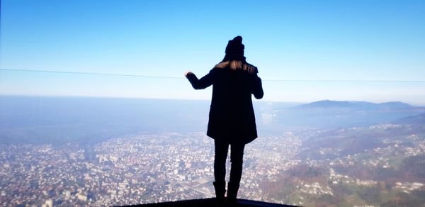 Rear view of man looking at cityscape against sky