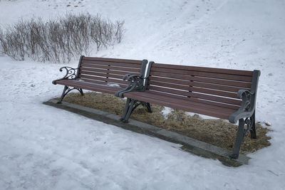 Empty bench on snow covered field during winter