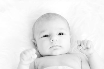 Portrait of cute baby girl lying on bed