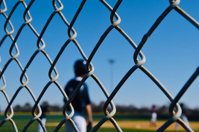 Full frame shot of  baseball player behind chainlink fence 