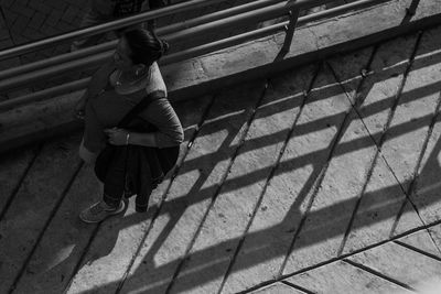 High angle view of woman walking on footbridge during sunny day