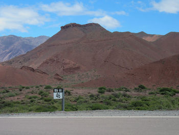 Road by mountains against sky