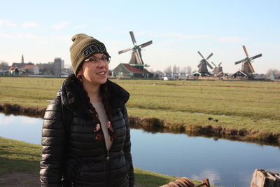 Young woman smiling while standing on field against sky