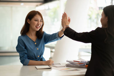 Portrait of smiling young woman using mobile phone at office