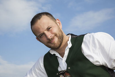 Low angle view portrait of man in traditional clothing standing against sky