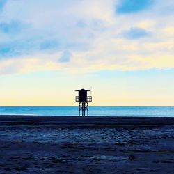 Lifeguard hut on beach against sky during sunset