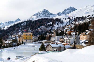 Snow covered houses and mountains against sky