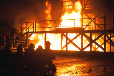 Silhouette firefighters spraying water on fire at night