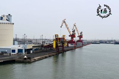 Cranes at commercial dock against clear sky