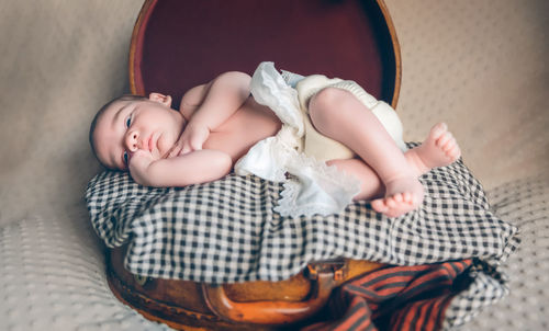 Baby girl lying on bed at home