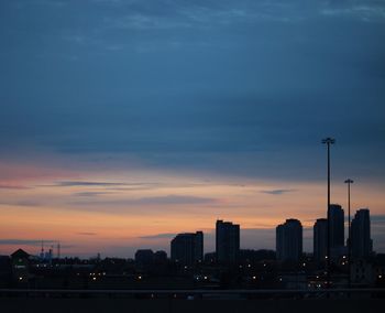 Illuminated cityscape against sky at sunset