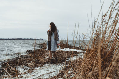 Woman standing by sea against sky