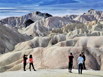 Rear view of people walking on mountain against sky