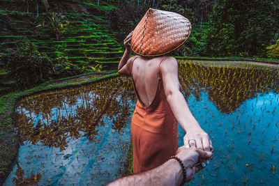 Midsection of woman holding hat against trees