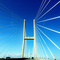 Low angle view of suspension bridge against blue sky