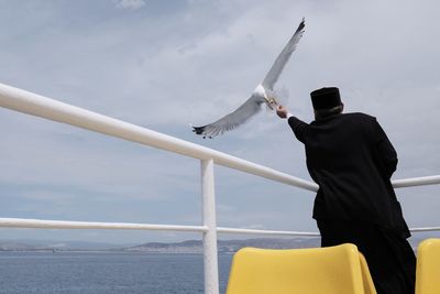 Rear view of man standing by sea against sky