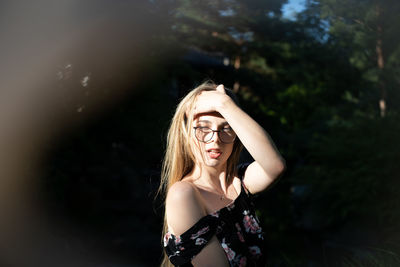 Portrait of beautiful young woman standing against blurred background