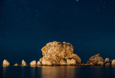 Rock formation in sea against sky at night