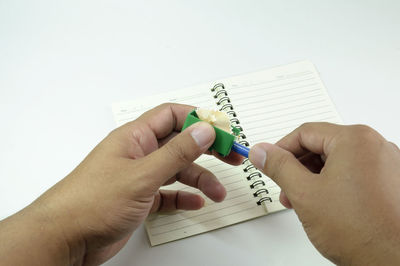 Midsection of person holding paper against white wall