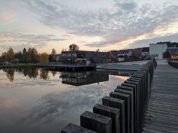 Scenic view of lake by buildings against sky at sunset