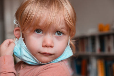 Close-up of cute girl wearing mask at home