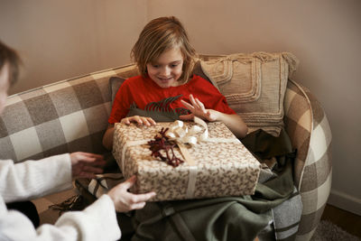 Boy sitting on sofa and opening christmas present