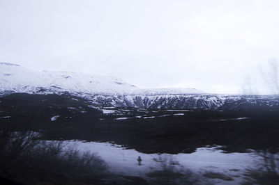 Scenic view of lake by snowcapped mountains against sky