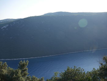 Scenic view of sea and mountains against clear sky