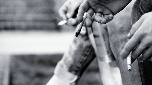 Cropped hands of friends holding cigarettes