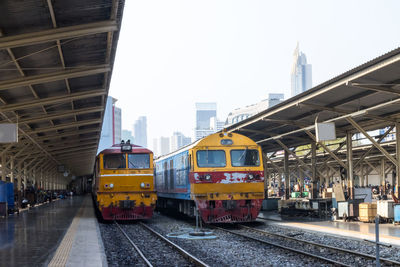 Train at railroad station in city against sky