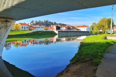 Buildings by river against sky