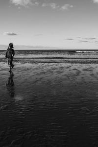 Woman standing on beach against sky