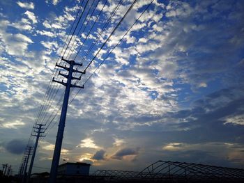 Low angle view of silhouette electricity pylon against sky