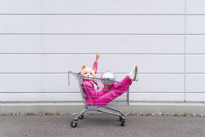 Girl sitting on pink wall